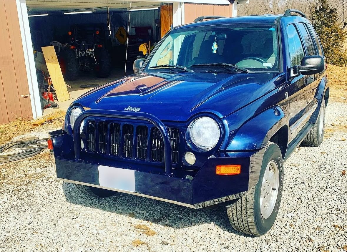 Blue Jeep with a custom steel front bumper and grille guard