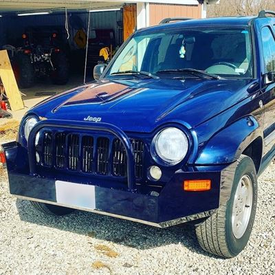 Blue Jeep with a custom steel front bumper and grille guard