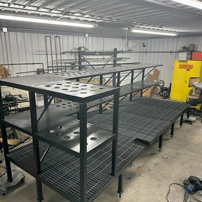 Long steel platform with grating decks and a tiered upper shelf, in the shop