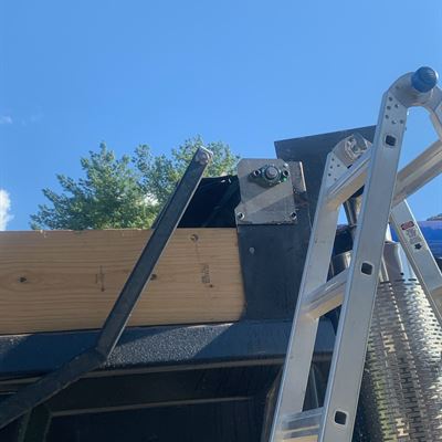 Tarp arm mount on the dump truck bed