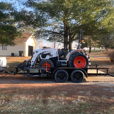 Utility trailer hauling a compact tractor